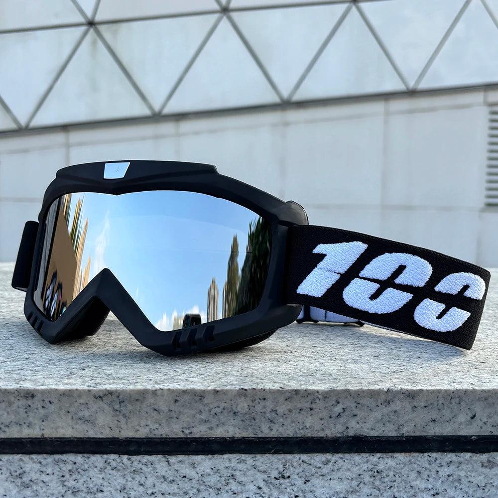 A pair of black windproof sports goggles with a white number 100 strap resting on a light gray surface.