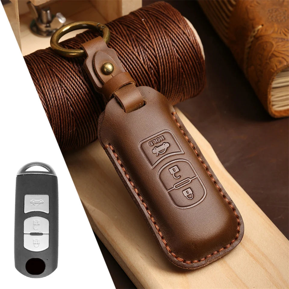 A brown leather car key fob cover attached to a coiled brown leather cord, resting on a wooden surface.