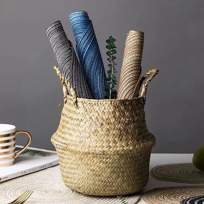 Un panier tissé rempli d'objets rayés en corde colorée et d'une tasse dorée sur une surface claire.