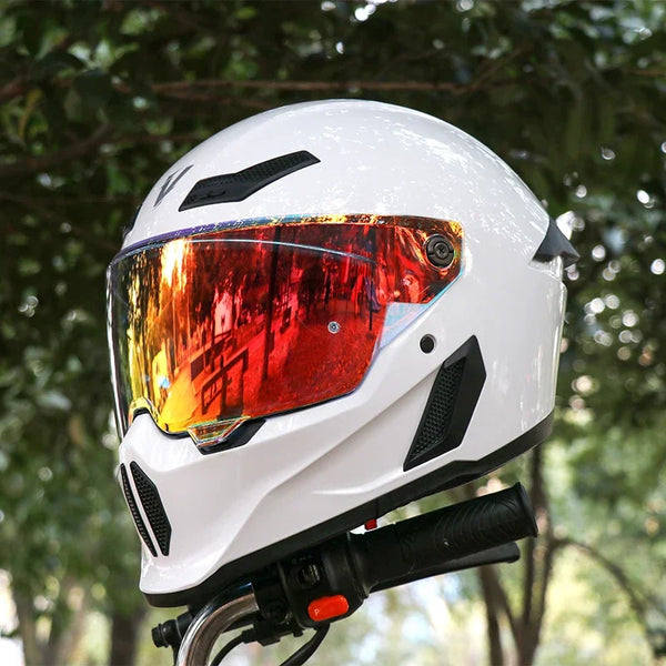 A white full face motorcycle helmet with an orange-tinted visor is shown against a blurred green background.