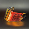 Visor de casco de motocicleta multicolor reflejando la luz, visto en ángulo contra fondo oscuro.