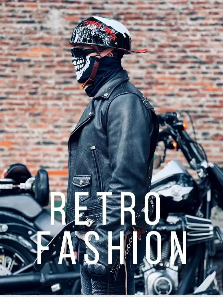 A person wearing a black leather jacket and a retro half helmet stands in front of motorcycles.