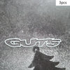 Three premium waterproof vinyl decals spelling out GUTS cast a shadow on a textured surface.