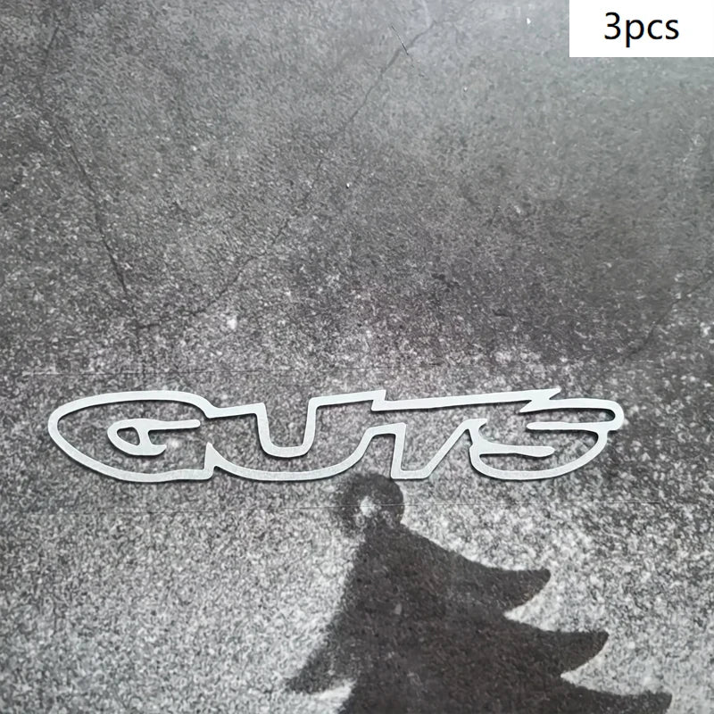 Three premium waterproof vinyl decals spelling out GUTS cast a shadow on a textured surface.