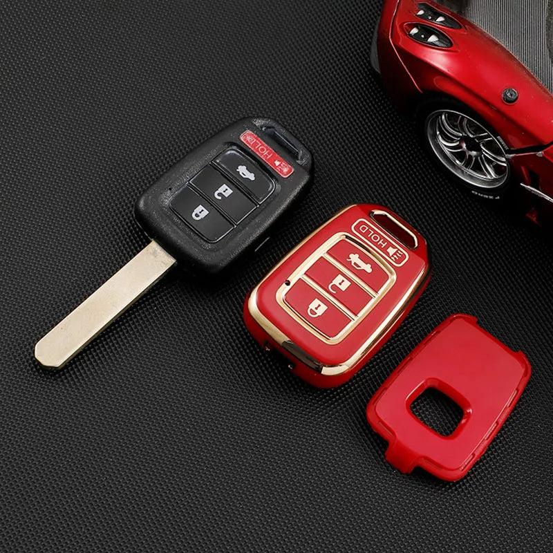 A red car key fob with a black cover and a metal key blade lying on a black surface.