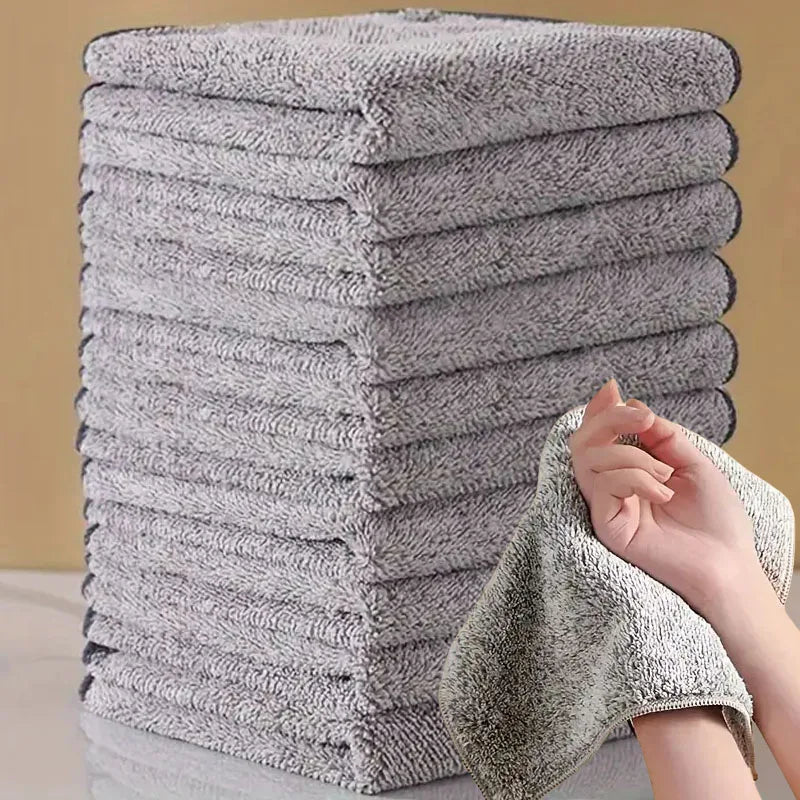 Ein Stapel grauer Mikrofasertücher neben einer Hand, die ein Tuch hält.