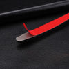 A red car door edge protection strip is shown lying on a black surface.
