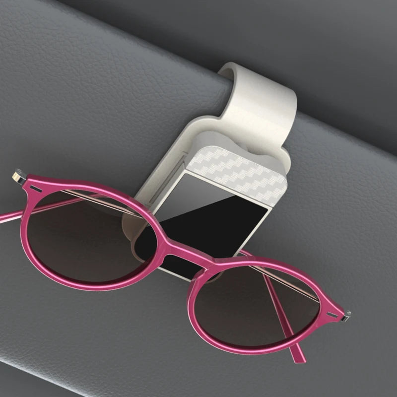 A pair of pink sunglasses resting on a white clip holder against a gray background.