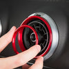 A hand is installing a red interior air vent trim cover into a black car vent.