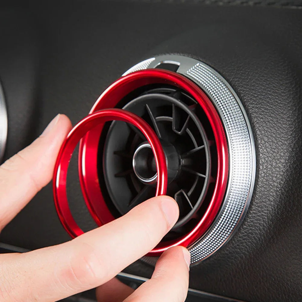 A hand is installing a red interior air vent trim cover into a black car vent.