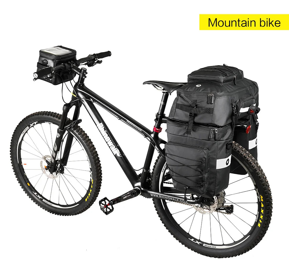 A black mountain bike equipped with a rear trunk bag and a front rack, ready for outdoor riding.
