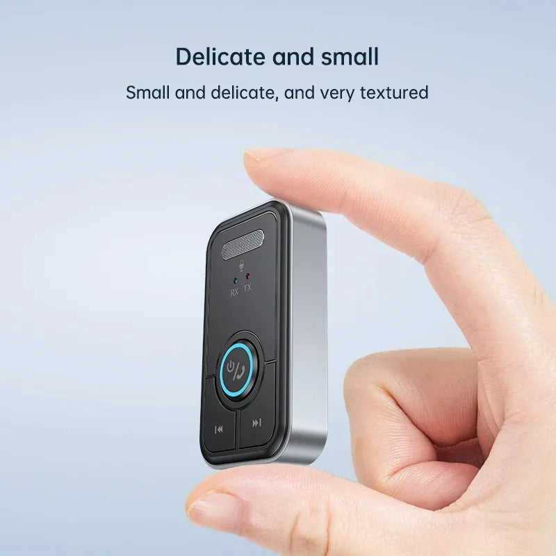 A hand holds a small, silver and black audio adapter device with a textured surface.