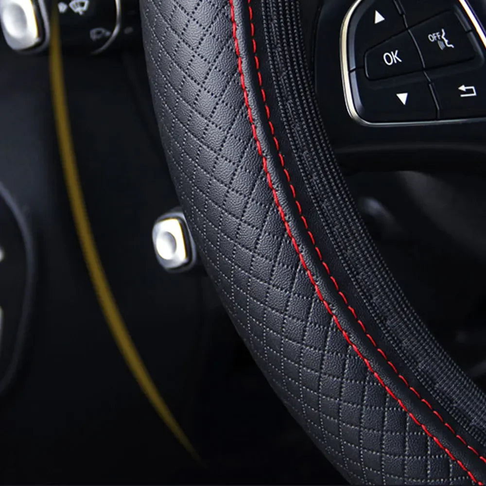 Close-up of a black quilted leather steering wheel cover with red stitching and controls visible.