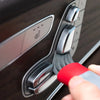 A hand is using a specialized brush to clean the air vent of a car interior.