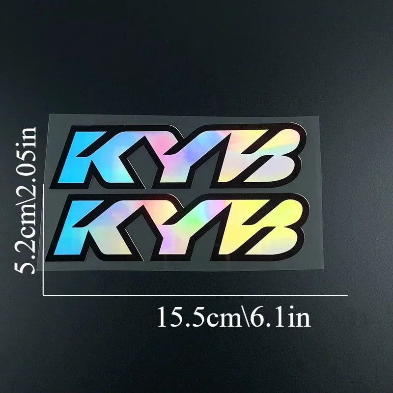 A set of four racing suspension decals featuring the letters KYB in various bright colors against a black background.