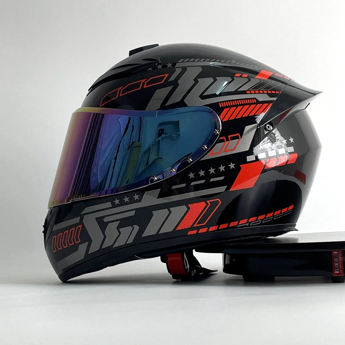 A black and red racing-style ABS motorcycle helmet is shown from the front, resting on a flat surface.