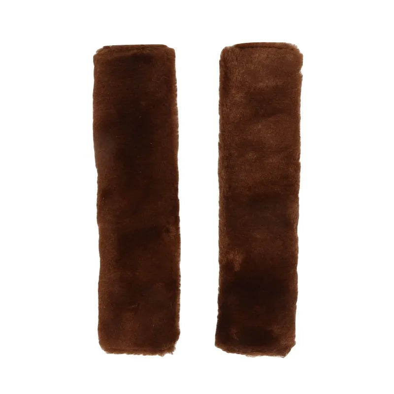 A pair of dark brown luxury car seatbelt shoulder pads.