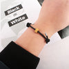 A close-up of a hand wearing a black heart-shaped fitness tracker bracelet on a wrist.