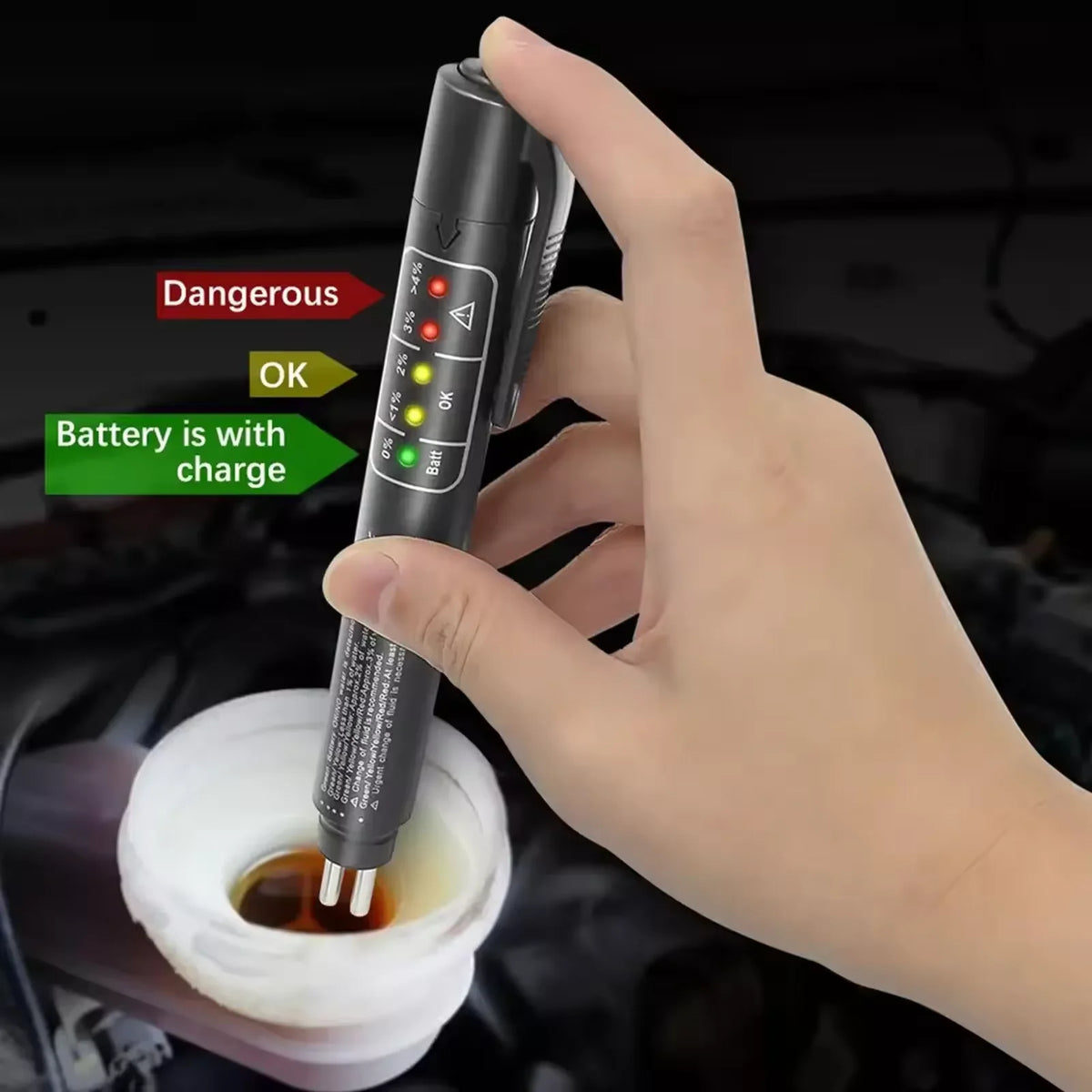 A hand holds a black brake fluid quality tester device, showing battery status indicators.