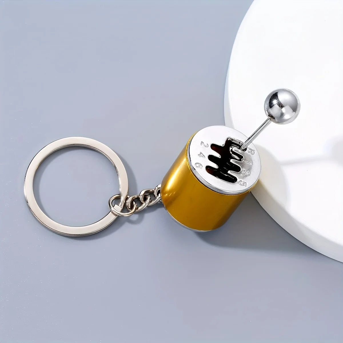A gold-colored creative car modification keychain with a silver ring and a spherical charm.
