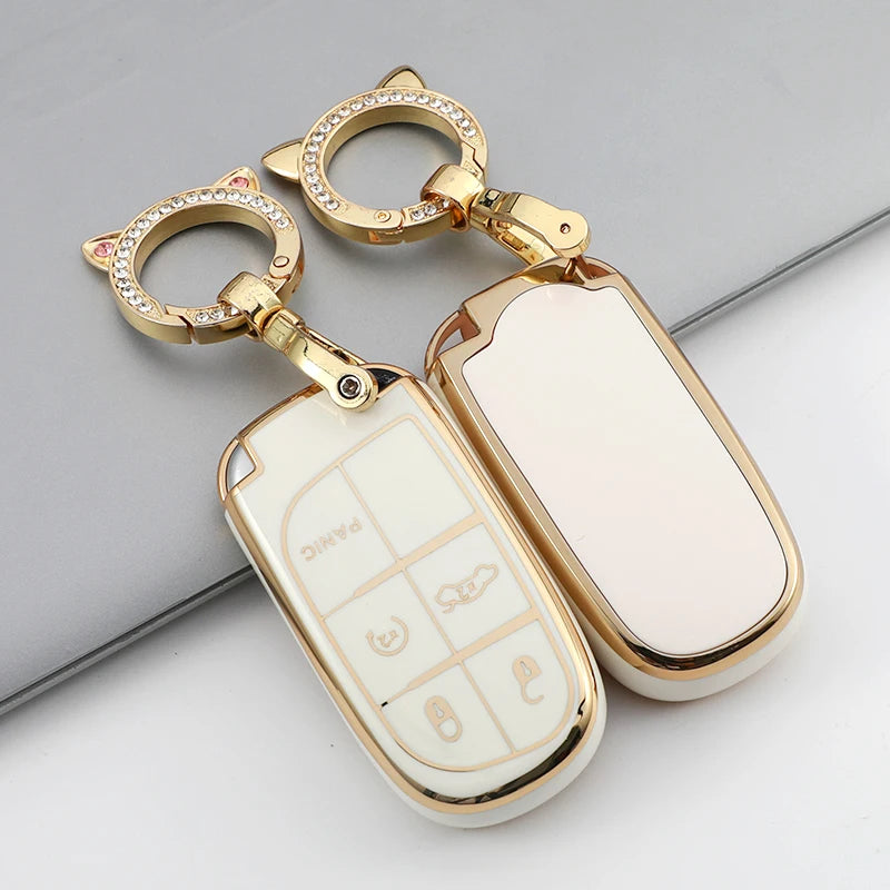 A gold-colored TPU car key case cover with a keyring and multiple key blanks is shown on a gray surface.