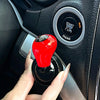 A hand is operating a red cylindrical car start button accessory on a vehicle's ignition switch.