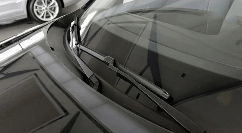 Nahaufnahme der Windschutzscheibe eines Autos mit Wischerblättern und umliegenden Glasskomponenten