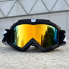 A pair of black windproof sports goggles with orange-tinted lenses resting on a gray surface.