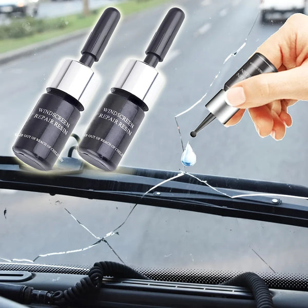 A hand applies a liquid resin from a kit onto a crack in a car windshield.