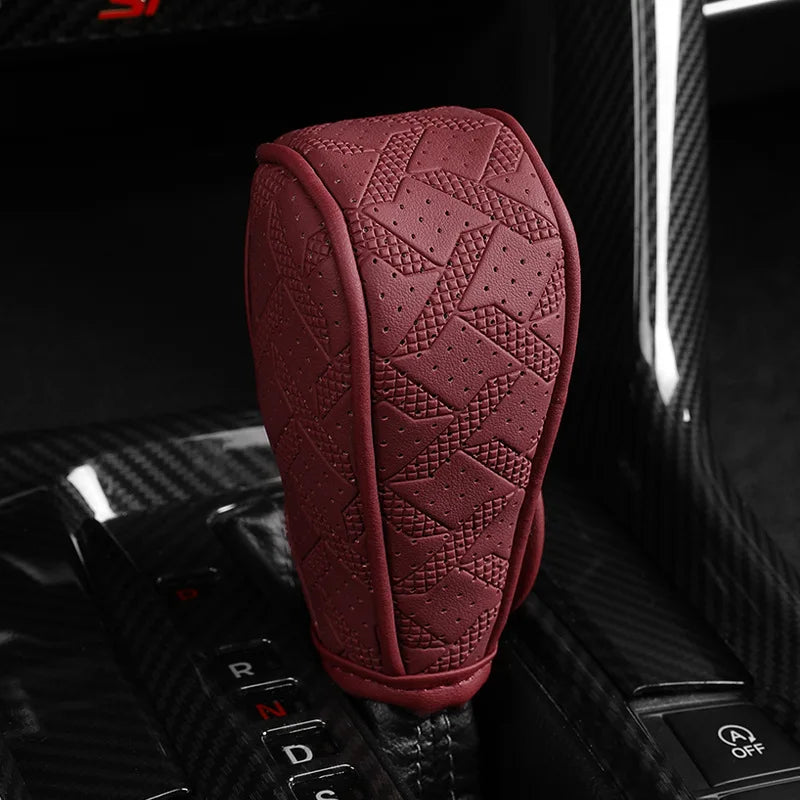 A maroon artificial leather handbrake cover resting on a black car interior surface.