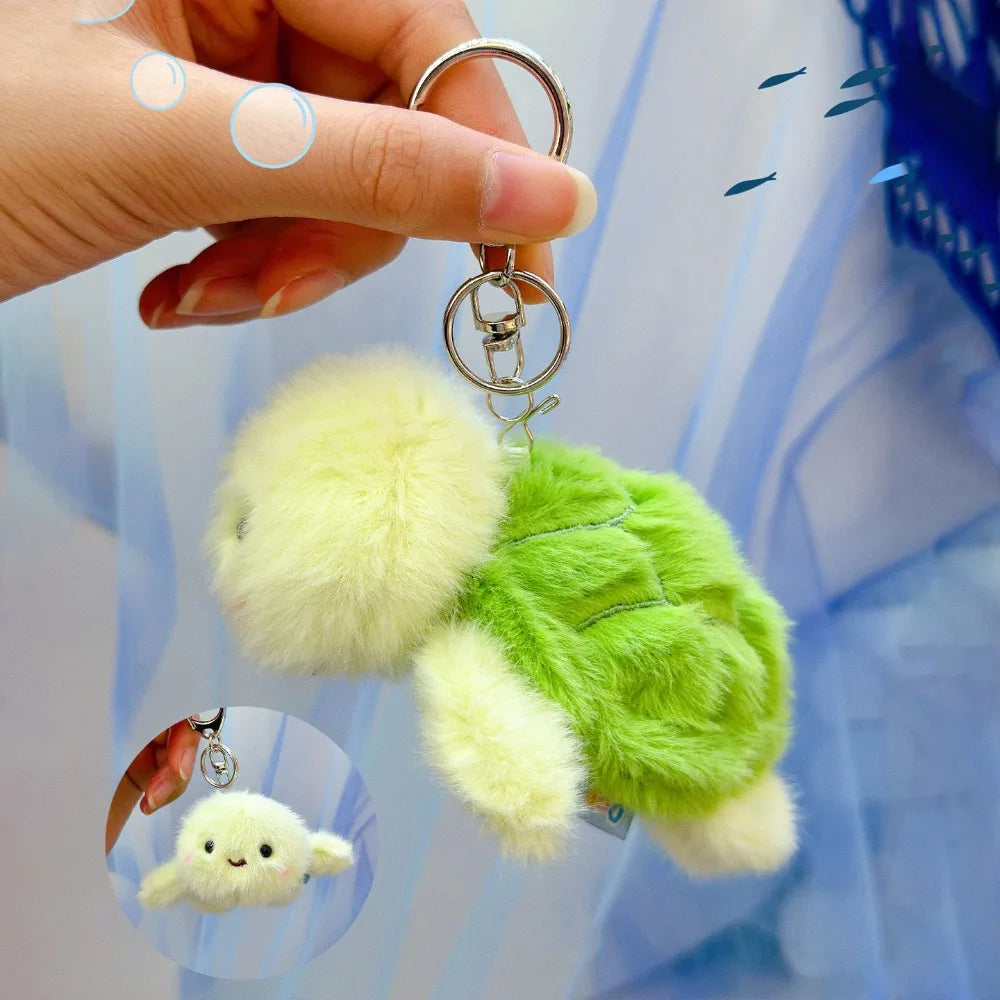 A hand is holding a green plush bunny keychain with soft yellow fur and a gold ring against a light blue background.
