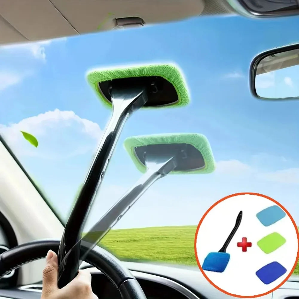 A hand holds a long-handle car window cleaning brush with green foam heads against a blue sky background.