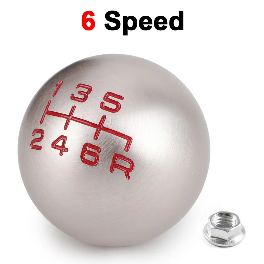 A silver aluminum gear shift knob with red markings showing 6 speed gears and an attached bolt.