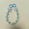 A necklace featuring round, light blue glass beads and white pearls with a decorative floral pendant.