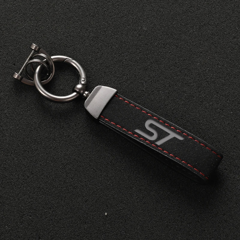 A black suede leather car keychain with a silver split ring and red stitching.