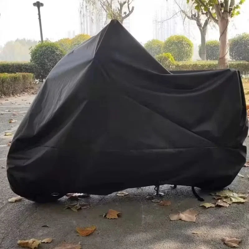 A black universal motorcycle protective cover is displayed on a paved surface outdoors.