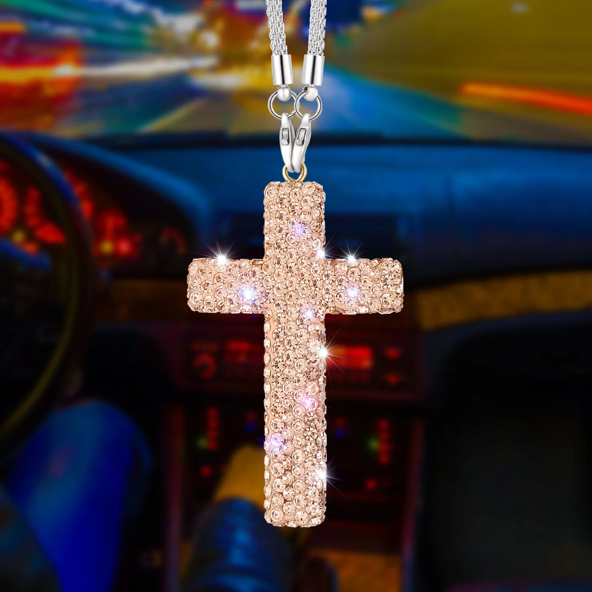 A gold-colored cross pendant with a textured surface hangs from a silver chain, set against a blurred car interior background