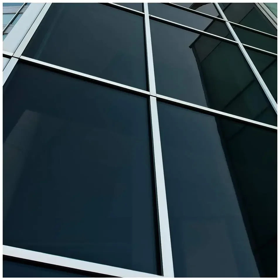 Nahaufnahme von dunkel getönten Glaspaneelen an der Fassade eines modernen Gebäudes.