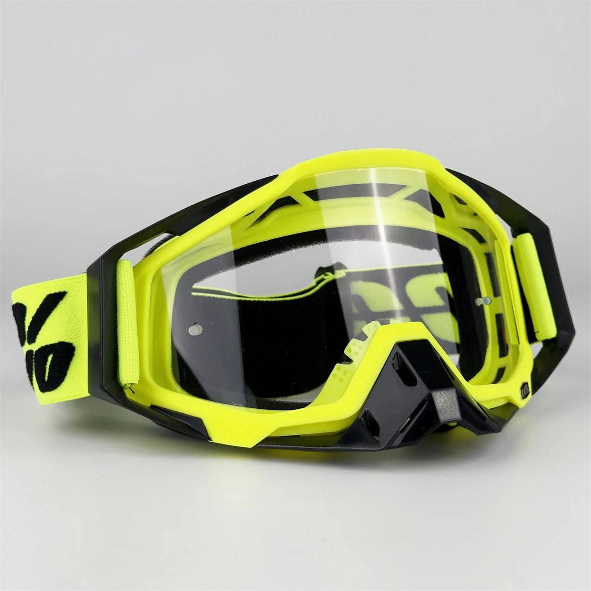 A pair of bright yellow and black off-road motorcycle riding goggles resting on a white surface.