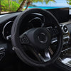 Close-up view of a black embossed leather steering wheel cover inside a car cockpit.