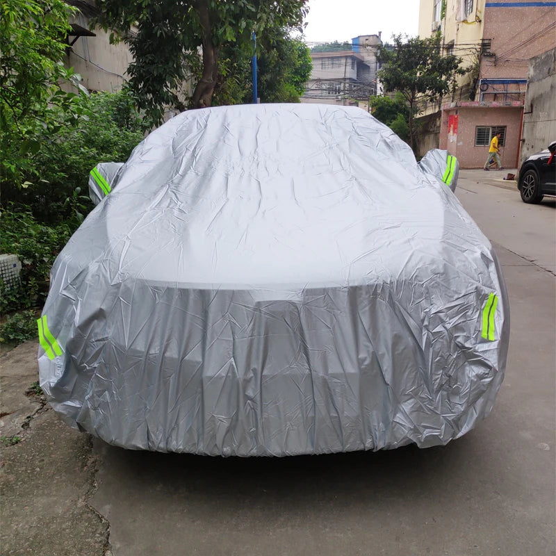 A silver universal all-weather car cover is draped over a vehicle, likely an SUV or sedan.