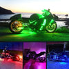 A green motorcycle is illuminated by bright RGB LED atmosphere lights in an outdoor setting.