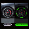 Close-up of a black car wheel with red brake calipers and green reflective decals on the spokes.