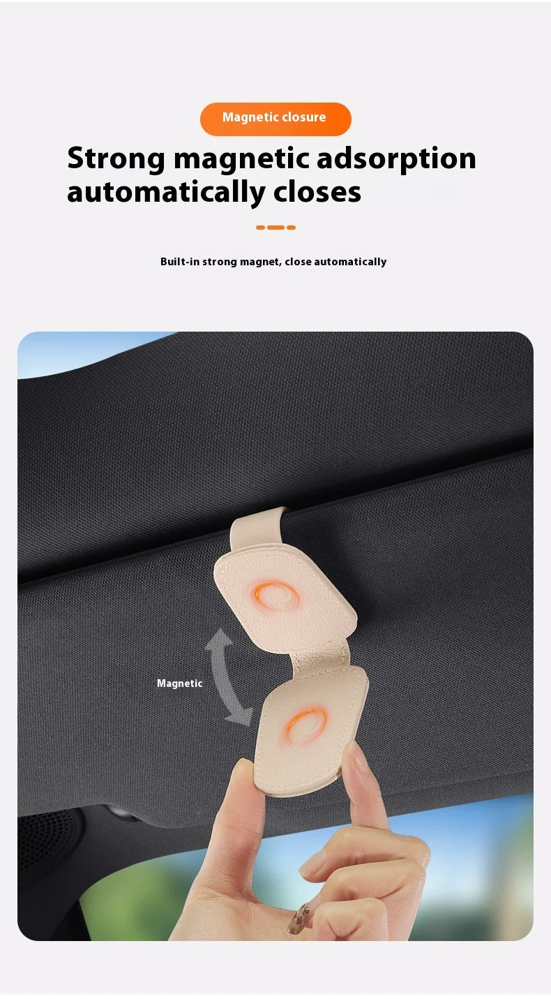 A hand is demonstrating a magnetic leather sunglasses holder that automatically closes onto a car sun visor.