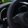 Close-up view of a black embossed leather steering wheel cover inside a car interior.