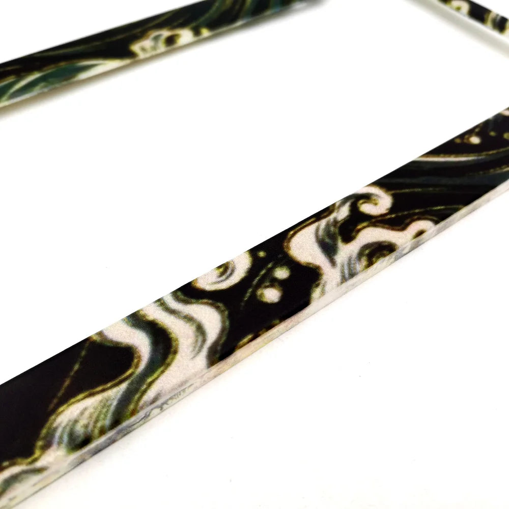 A close-up of a black and white marbled license plate frame decoration.