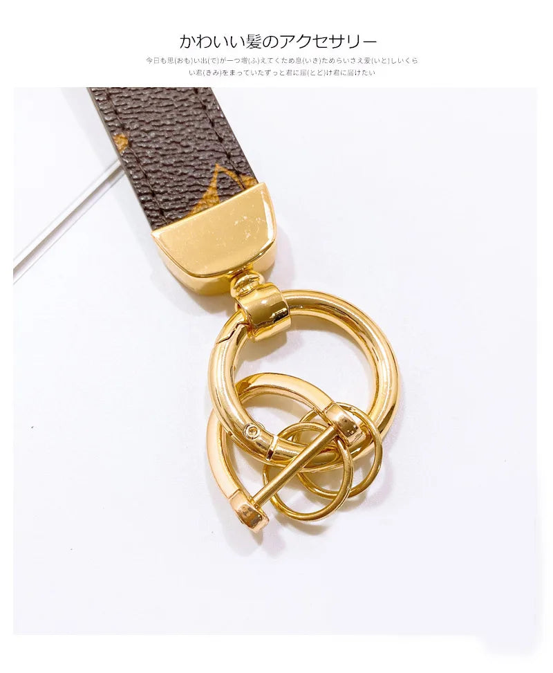 Llavero de cuero tono dorado con correa de estampado de serpiente leopardo marrón oscuro y anillo circular dorado.