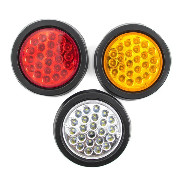 A set of three round LED trailer lights including a red brake light, yellow turn signal, and clear fog light.