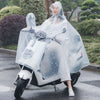 A person wearing a transparent windproof motorcycle rain poncho is sitting on a motorcycle on a wet road.
