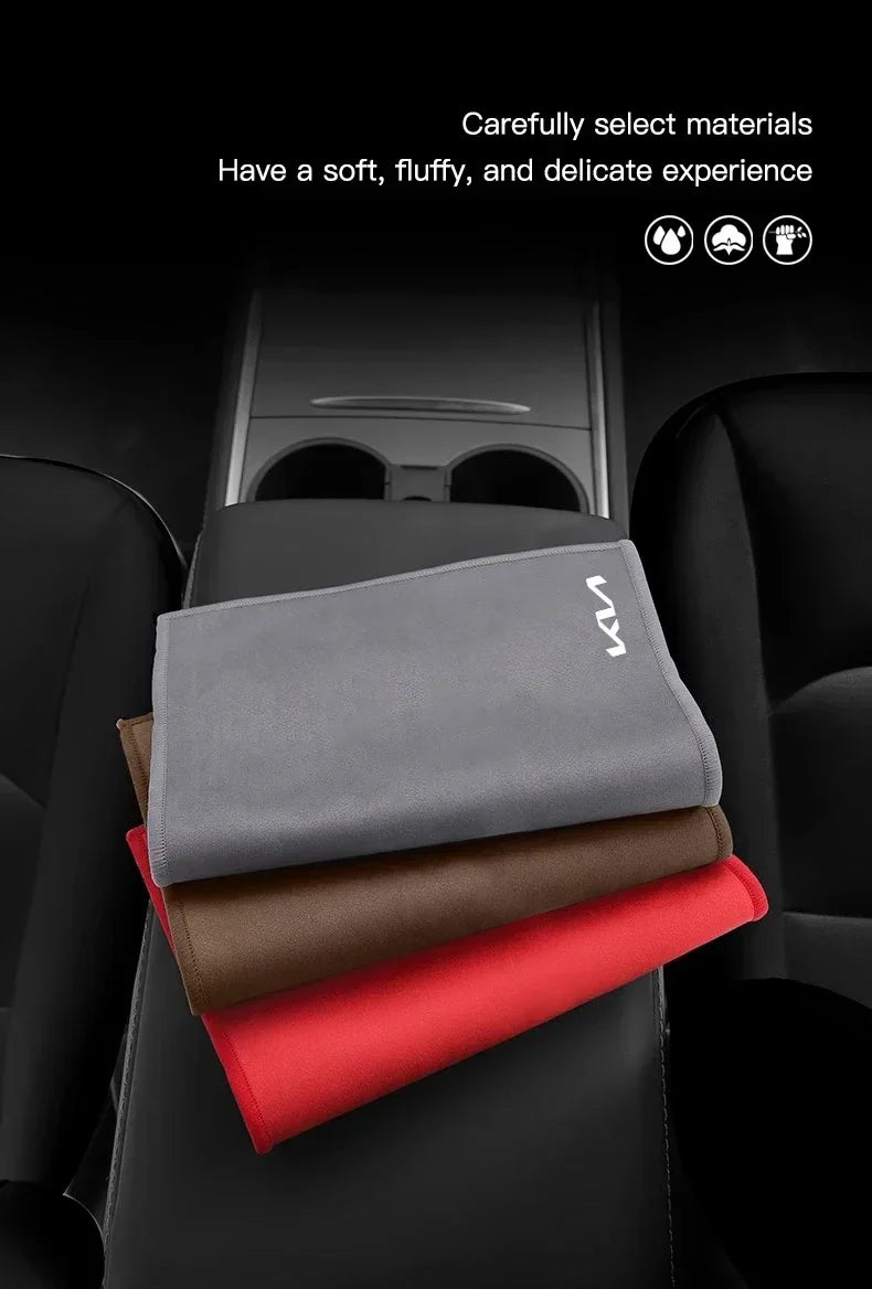 Un ensemble de serviettes en microfibre gris et marron et une brosse de nettoyage sur un siège de voiture noir.